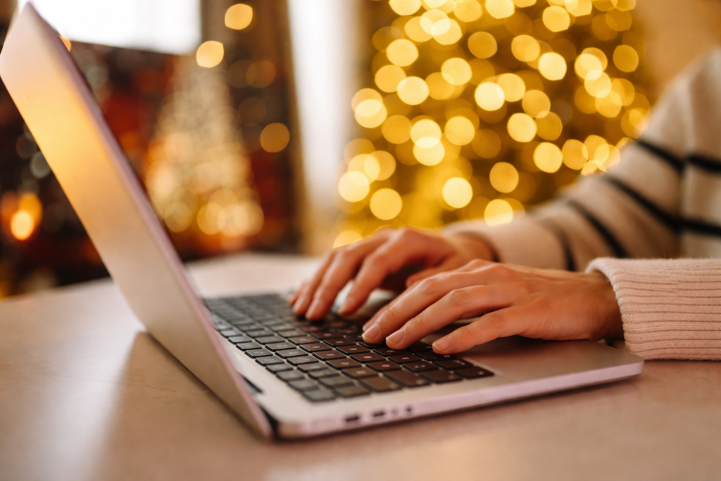 Práce na notebooku v teplém vánočním prostředí, symbol klidného pracovního tempa a soustředění na konci roku